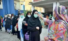  ?? APP file ?? A teacher checks temperatur­es of students at a school in Peshawar. —