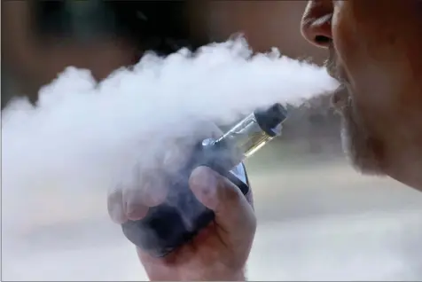  ?? ROBERT F. BUKATY ?? File - In this Aug. 28, 2019, file photo, a man exhales while smoking an e-cigarette in Portland, Maine. The U.S. government has refined how it is measuring an outbreak of breathing illnesses in people who vape, now counting only cases that are most closely linked to electronic cigarette use. Health officials on Thursday, Sept. 12, 2019 said 380 confirmed cases and probable cases have been reported in 36 states and one U.S. territory.