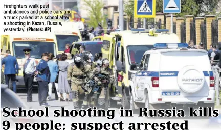  ?? (Photos: AP) ?? Firefighte­rs walk past ambulances and police cars and a truck parked at a school after a shooting in Kazan, Russia, yesterday.