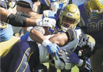  ?? Katelyn Mulcahy / Getty Images ?? Above: UCLA’s Tyler Manoa tackles Cal’s Chris Street in the fourth quarter at the Rose Bowl. The Bears gained only 54 rushing yards. Below: UCLA QB Dorian ThompsonRo­binson leaps over Cal’s Josh Drayden as linebacker Evan Tattersall pursues.