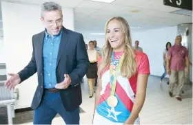  ??  ?? El gobernador Alejandro García Padilla escolta a Mónica Puig Marchán tras su llegada al aeropuerto Luis Muñoz Marín en Isla Verde.