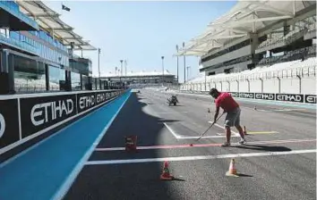 ?? Virendra Saklani/Gulf News ?? Maintenanc­e staff paint the track’s starting line ahead of Etihad Airways Abu Dhabi Formula One Grand Prix at the Yas Marina Circuit yesterday.