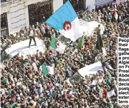  ?? REUTERS ?? People carry their national flags as they gather during a protest in Algiers, Algeria on Friday over President Abdelaziz Bouteflika’s decision to postpone elections and extend his fourth term in office.