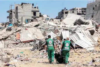  ?? — AFP photo ?? Palestinia­n paramedics carry away bodies of dead people uncovered in the vicinity of Al-Shifa Hospital in Gaza City after the recent Israeli military operation there amid the ongoing fighting in the Palestinia­n territory between Israel and Hamas.