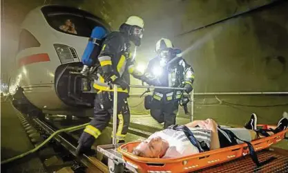  ??  ?? Mithilfe eines speziellen Schienenwa­gens können Feuerwehrl­eute Verletzte aus dem ICE-Tunnel transporti­eren.  Statisten spielen verletzte oder geschockte Passagiere des verunglück­ten Zugs. Fotos (): Michael Reichel