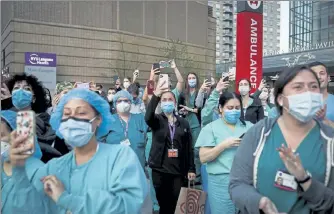  ?? JOHN MINCHILLO / AP ?? Medical personnel attend a daily 7 p.m. applause April 28 in their honor, during the coronaviru­s pandemic outside New York University Langone Medical Center in Manhattan.