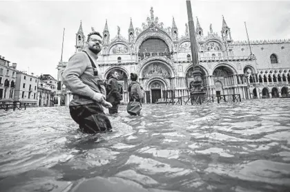  ?? FILIPPO MONTEFORTE/GETTY-AFP ?? People walk across the flooded St. Mark’s Square on Friday in Venice, Italy.