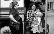  ?? LOREN ELLIOTT/GETTY-AFP ?? A woman carries a baby as migrants are dropped off last month at a bus station after being released in Texas.