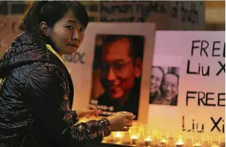  ?? Steven Saphore/Reuters ?? Tibetana na Austrália acende vela em vigília em homenagem ao Nobel da Paz Liu Xiaobo