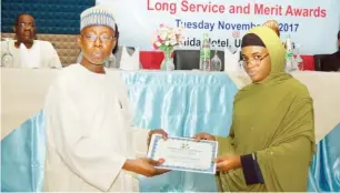  ??  ?? Media Trust’s Executive Director, Alh. Aminu Dangana presents the 15year long service award to Rakiya A. Mohammed of Editorial Department