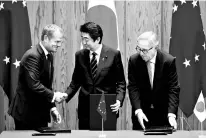  ?? PHOTO: REUTERS ?? Japanese PM Shinzo Abe (centre) shakes hands with European Commission President Jean-Claude Juncker and European Council President Donald Tusk after signing the FTA in Tokyo