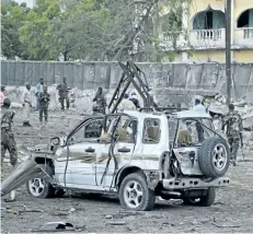  ?? FARAH ABDI WARSAMEH/THE ASSOCIATED PRESS ?? Somali soldiers stand near the wreckage of a vehicle after a car bomb attack that targeted a checkpoint in Mogadishu, Somalia, on Tuesday. At least five people were killed.