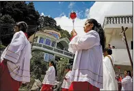  ?? Los Angeles Times/MARCUS YAM ?? A church procession passes homes in Todos Santos, Guatemala, that were built in a grandiose style known as remittance architectu­re, funded with money townspeopl­e earned in the United States.