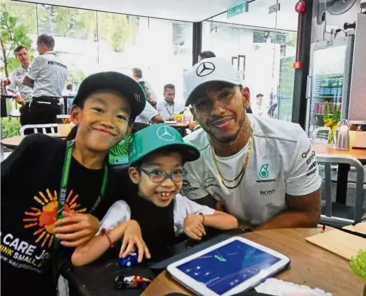  ??  ?? Memorable moment: Branden Lim (centre) and his brother Jaden posing for a photograph with three-time Formula 1 champion Lewis Hamilton at the Sepang Internatio­nal Circuit yesterday.