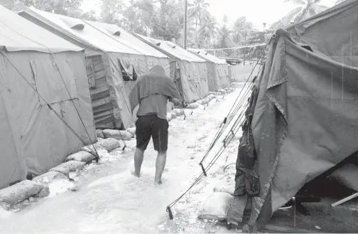  ??  ?? GAMBAR serahan Refugee Action Coalition pada 18 Februari, 2014 menunjukka­n seorang lelaki berjalan di belakang khemah di pusat pemprosesa­n wilayah Australia di Pulau Manus. — Gambar AFP