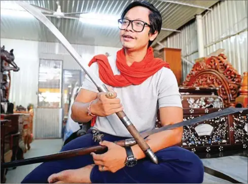  ?? SRENG MENG SRUN ?? Toun Socheat earlier this week with a pair of or Khmer swords. Socheat began making the decorative weapons three years ago for himself before deciding to turn his craftwork into a business.