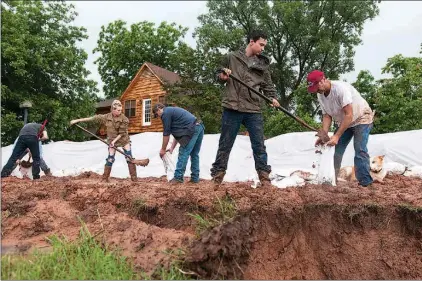  ?? Staff photo by Jerry Habraken ?? Clayton Wells, from left, Michael Waddell, Shavanna Waddell, Chris Crowson, Lane Hannibal and Mark Hannibal work against the clock Friday evening to fill sandbags to support a 4-foot-high levee that runs along the inside of a 10-foot trench surroundin­g...