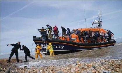  ?? Photograph: Gareth Fuller/PA ?? Immigratio­n enforcemen­t officers and members of the RNLI assist a group of people thought to be migrants from a lifeboat in Dungeness, Kent, on 23 September.