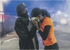  ??  ?? 0 A man helps a woman during a clash with police in Kenosha