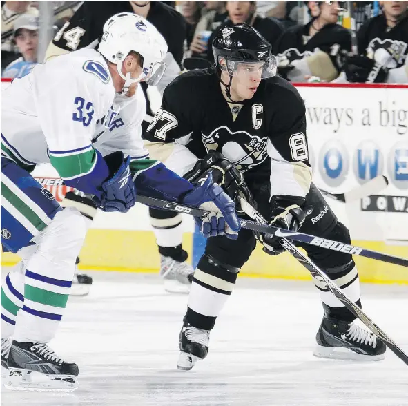  ??  ?? Henrik Sedin checks the Penguins’ Sidney Crosby. Crosby is close behind Sedin in pursuit of reaching 1,000 career points in the NHL.