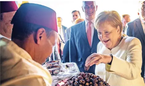 ?? FOTO: DPA ?? Freut sich über Datteln: Bundeskanz­lerin Angela Merkel bedient sich nach der Ankunft am Flughafen Marrakesch-Menara.