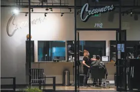  ?? Photos by Tony Avelar / Special to the Chronicle ?? Kelli Ballin, a barber at Crewners Barber Shop in San Jose, cuts a client’s hair late into the night on Tuesday. Santa Clara County opened barbershop­s and salons on Monday and on the same day ordered them to close by Wednesday.