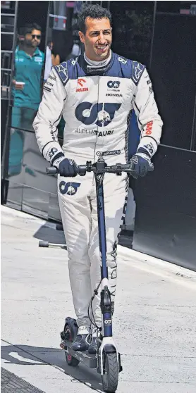  ?? ?? Racing back: Daniel Ricciardo rides a scooter in the pits at the Hungarorin­g