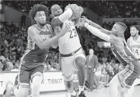  ?? ASSOCIATED PRESS ?? Los Angeles Lakers forward LeBron James drives the ball between Sacramento Kings forward Marvin Bagley III, left, and guard Frank Mason III during the first half of an NBA preseason basketball game in Los Angeles.