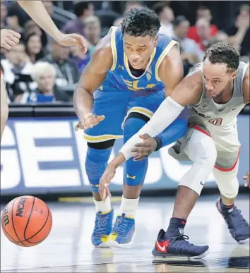  ?? Isaac Brekken Associated Press ?? UCLA’S AARON HOLIDAY and Arizona’s Parker Jackson-Cartwright go after a loose ball during the first half at Las Vegas. Holiday scored 15 points, but he made only five of 20 shots against the Wildcats.