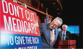  ?? MANUEL BALCE CENETA/AP PHOTO ?? Senate Minority Leader Chuck Schumer of New York, followed by Sen. Bernie Sanders, I-Vt., looks at a poster at the start of a news conference on Capitol Hill in Washington, Wednesday, urging Republican­s to abandon cuts to Medicare and Medicaid.