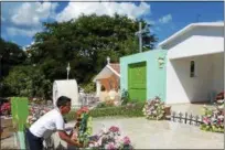  ?? JANET PODOLAK— THE NEWS-HERALD ?? A boy, who has just finished sweeping, decorates a family grave with flowers to prepare for the Day of Dead in a Mazatlan cemetery.