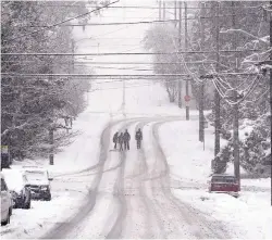  ?? ELAINE THOMPSON/ASSOCIATED PRESS ?? Pedestrian­s cross a street as heavy snow falls Monday in Seattle. A large weather system wreaked havoc in the region and even brought snow to Hawaii.