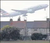  ??  ?? An airplane takes off over the rooftops of nearby houses at Heathrow Airport