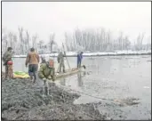  ??  ?? Dar (foreground) breaks ice with other wildlife officials in the frozen surface of a wetland.