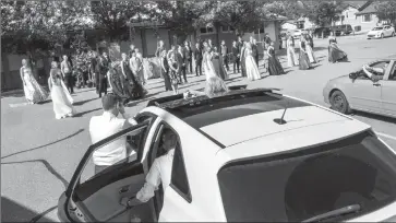  ?? Herald photo by Ian Martens @IMartensHe­rald ?? Family members lean out of their vehicles to get photos of a socially distant group portrait of the graduation class at the end of a drive-in grad ceremony for Immanuel Christian High School Friday in the parking lot at Trinity Reformed Church.