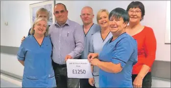  ??  ?? Andrew Spence presents £1,250 to Margaret Blue and other hospital staff.