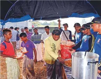  ?? AP ?? Refugee Fariq Mohammad (centre) helps to distribute food to other Rohingya Muslims rescued off Indonesian waters in a wooden boat, during breakfast at a temporary shelter in Bireun, Aceh province, Indonesia, yesterday. Mohammad said they were at sea...
