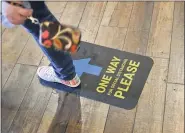  ?? MEDIANEWS GROUP FILE PHOTO ?? A person walks over signs on the floor asking people to follow a particular direction of travel and to maintain 6 feet of social distance at P.J. Whelihan’s in Spring Township June 9, 2020, where they now have dine-in service at their outdoor patio, and at tables they have setup in a roped off portion of their parking lot. They have markings on the floors indicating which way to travel when inside for the bathroom, and staff regularly disinfect surfaces. The restaurant had been closed during the shutdown precaution­s against the spread of coronaviru­s.