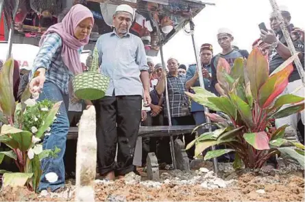  ?? [FOTO SHARUL HAFIZ ZAM /BH] ?? Nurul Najihah ditemani Mohd Kassim menabur bunga di pusara Muhammad Adib di Tanah Perkuburan Masjid As-saadah di Kampung Tebengau, Kuala Kedah, semalam.