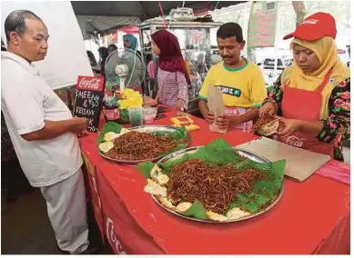  ??  ?? MARSHIDAH (kanan) melayan pelanggan membeli mi dan kuetiau tonggek di Bazar Ramadan Hospital Sultanah Bahiyah.