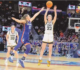  ?? ASSOCIATED PRESS ?? Iowa guard Caitlin Clark (22) shoots a 3-point basket over UConn guard Nika Muhl (10) during the second half of an NCAA Tournament Final Four game Friday in Cleveland.