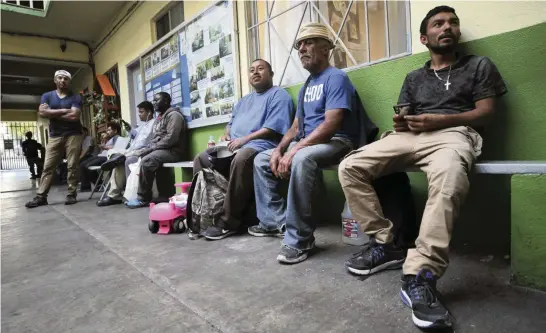  ?? HAYNE PALMOUR IV The San Diego Union-Tribune/TNS ?? Men sit at a shelter for migrants, asylum-seekers and deportees in 2019 in Tijuana, Mexico. Thousands of asylum-seekers have been stuck in the border city for months, and in some cases years, because of restrictiv­e policies from the Trump administra­tion.