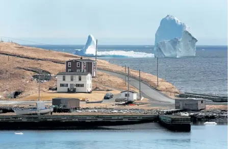  ?? PAUL DALY/THE CANADIAN PRESS ?? A large iceberg is visible from the shore in Ferryland, NL earlier this month. The towering iceberg stationed off Newfoundla­nd's east coast is drawing dozens of people to the small shoreline community sitting in its shadow. It's another example of the...