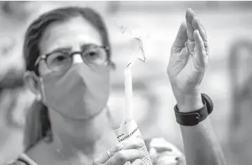  ?? RAMON ESPINOSA/AP ?? Feast day in Cuba: In Havana, a woman holds a candle during a Mass radio broadcast Tuesday in honor of the Virgin of Charity of Cobre, or Our Lady of Charity, the patron saint of Cuba. Havana remains under a nighttime curfew due to the new cornavirus pandemic. Cuba has reported 4,309 infections and 100 deaths from the disease since March.