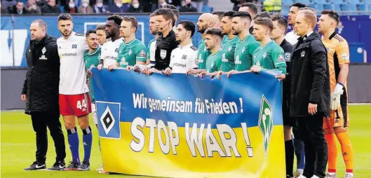  ?? BILD: Imago ?? Gemeinsame Minute des Innehalten­s: Nach dem Angriff Russlands auf die Ukraine halten Hamburger und Bremer Spieler ein Banner mit der Aufschrift „Wir gemeinsam für Frieden! Stop War!“kurz vor dem Anpfiff hoch.