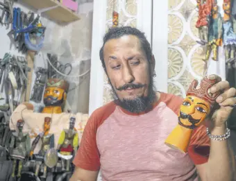  ??  ?? Adel el-Ashi looks at a janissary puppet he made in their workshop in the capital Tunis, Tunisia, Oct. 10, 2020.