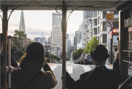  ?? Photos by Jessica Christian / The Chronicle ?? Riders take pictures as they look down California Street toward the bay while aboard a Powell Street cable car.