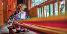  ??  ?? Li Wenshi, a woman of the Derung ethnic group, weaves a blanket in Dulongjian­g Township in Gongshan Derung and Nu Autonomous County.