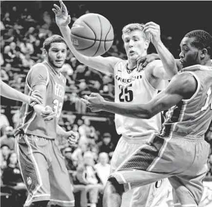  ?? SCOTT OLMOS/USA TODAY SPORTS ?? Oregon forward E.J. Singler (25) reaches for the ball between Houston Baptist defenders during Saturday’s game in Eugene, Ore. Singler scored 13 points to help the Ducks to the win, as the defense held Houston Baptist to just 26 percent from the field.