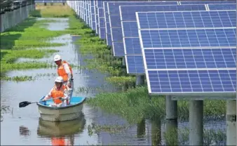  ?? ZHOU GUOQIANG / FOR CHINA DAILY ?? Two electricia­ns paddle through a fishery where a photovolta­ic power station was set up, in Jiangling county, Hubei province.